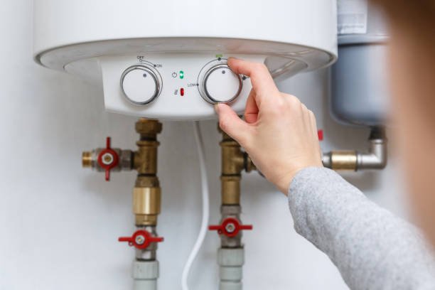 Female hand puts thermostat of electric heater